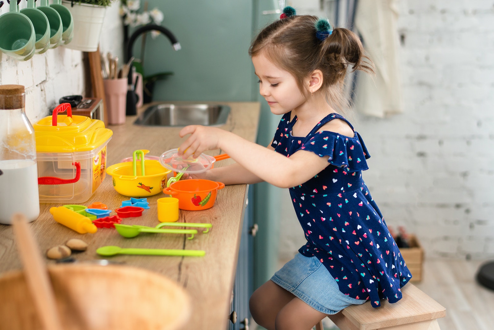 Girl Playing with Her Cooking Tools (Toys) on the Kitchen Counter