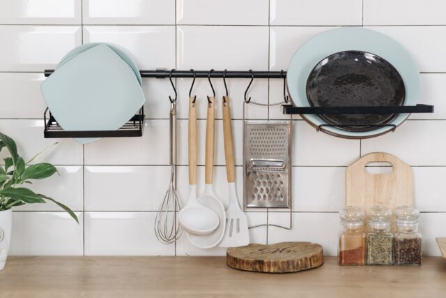 Plates and Utensils on White Wall and Spices on Wooden Surface - Cooking Tools